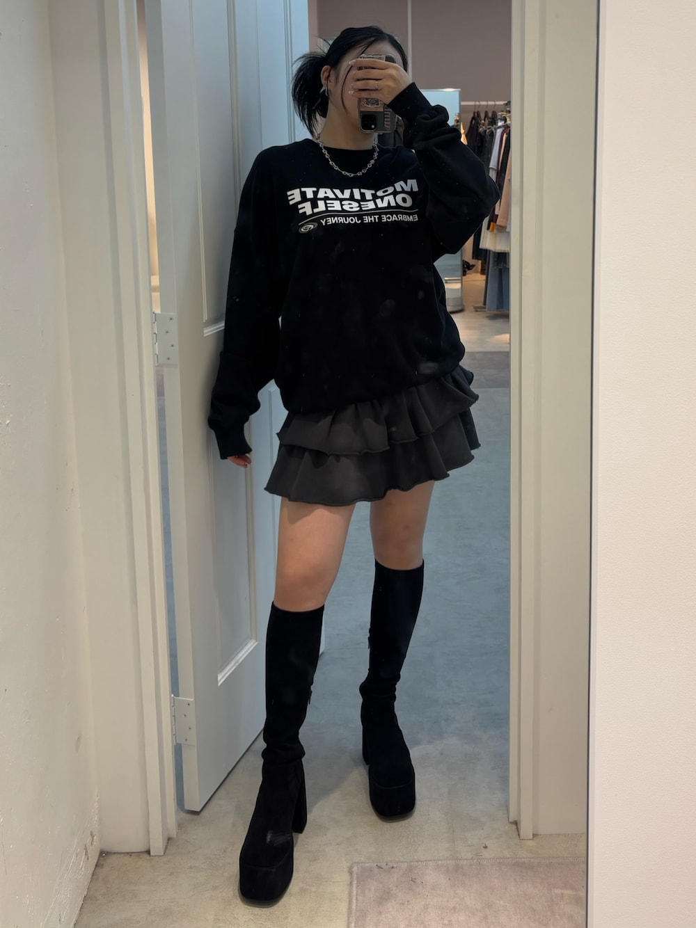 グレー系のスカート、ブラック系のブーツ、ブラック系のスウェットを着用したレディースの夏コーディネートの1枚目の写真
