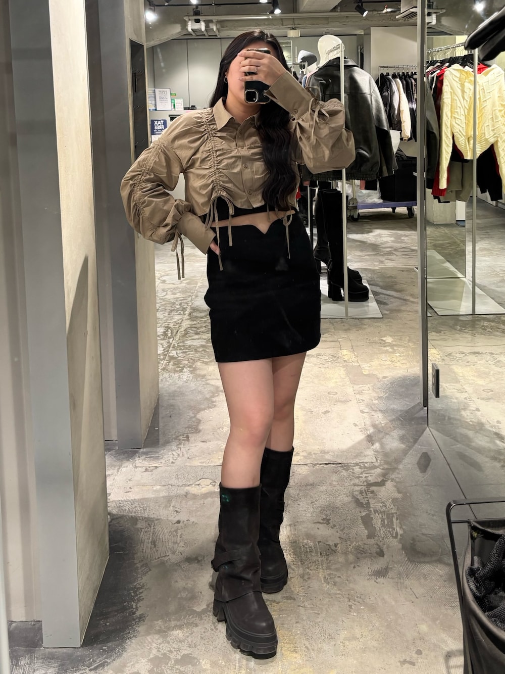 ブラック系のブーツ、ブラック系のスカート、ベージュ系のシャツ/ブラウスを着用したレディースの春コーディネートの1枚目の写真