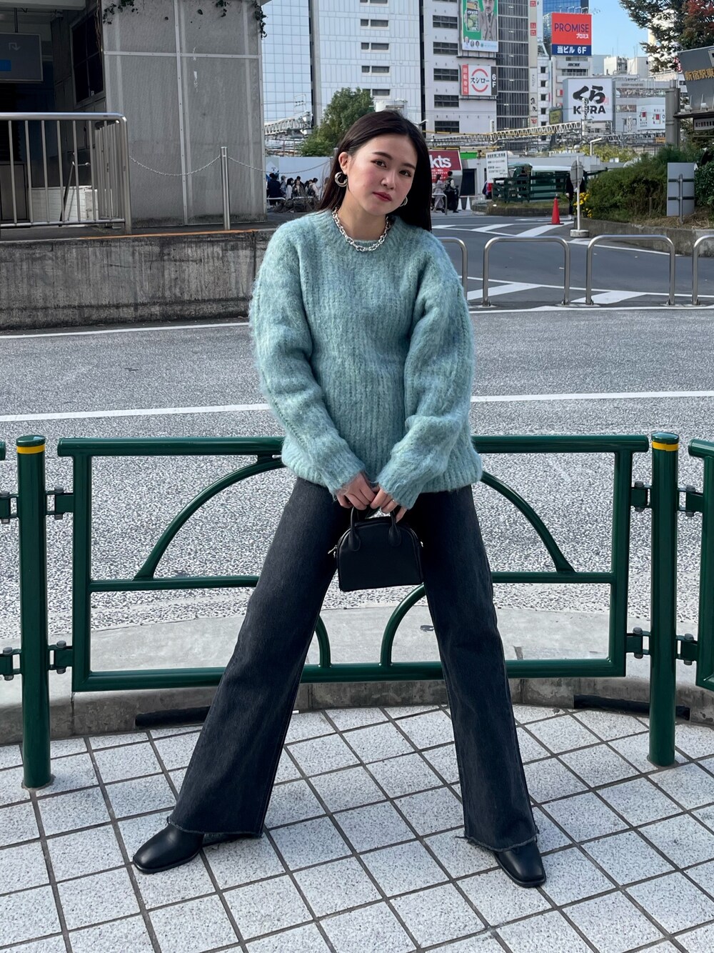 ブルー系のニット/セーター、ブラック系のデニムパンツ、ブラック系のブーツを着用したレディースの秋コーディネートの1枚目の写真