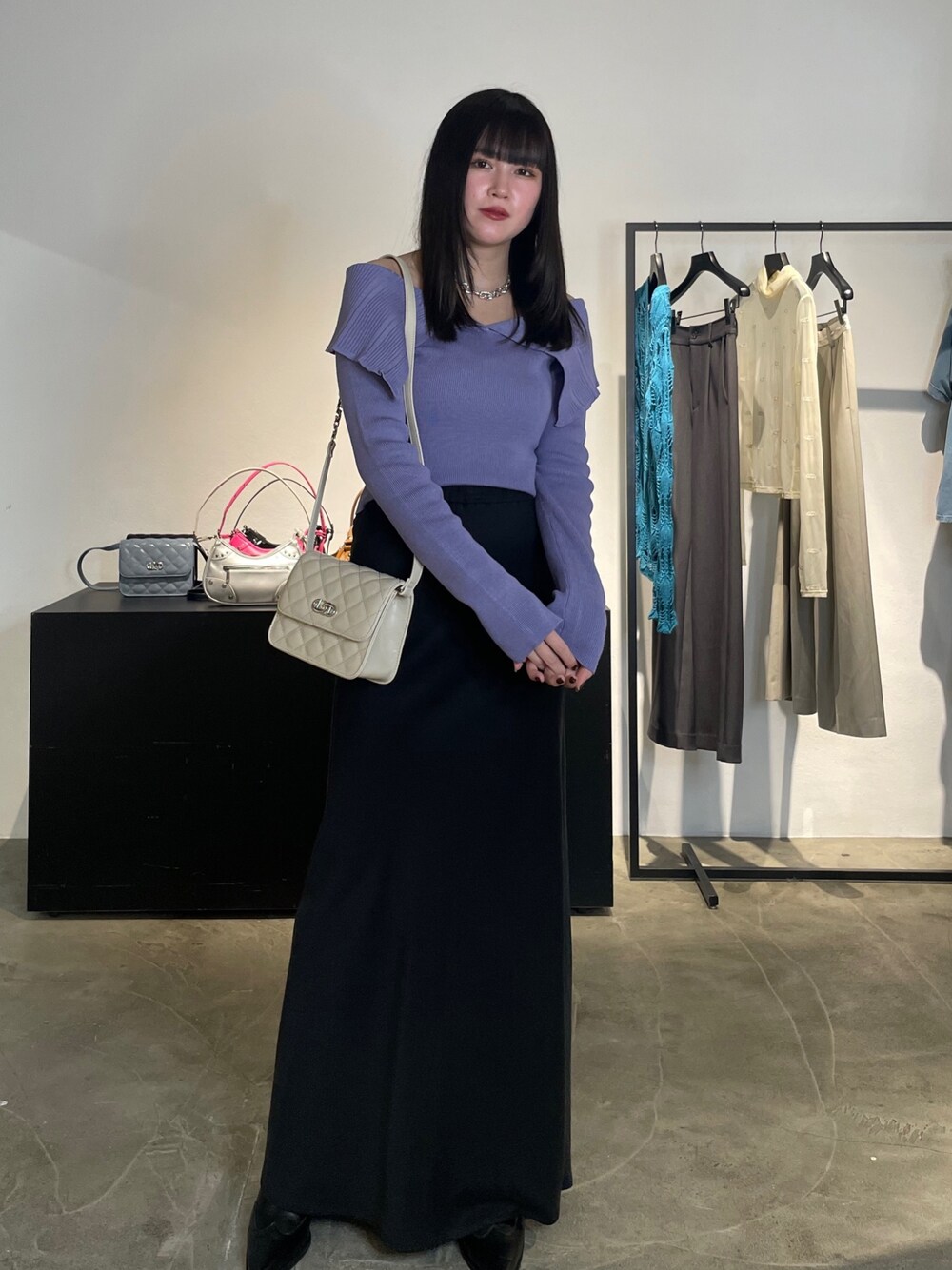 ブラック系のスカート、ブラック系のブーツ、パープル系のニット/セーターを着用したレディースの春コーディネートの1枚目の写真