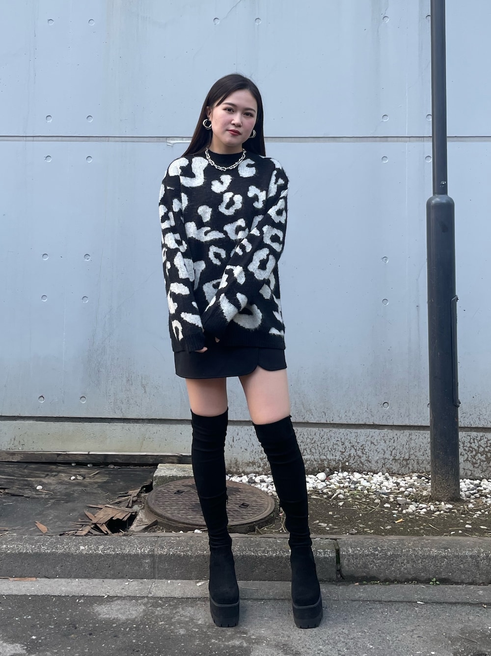 ブラック系のニット/セーター、ブラック系のスカート、ブラック系のブーツを着用したレディースの冬コーディネートの1枚目の写真