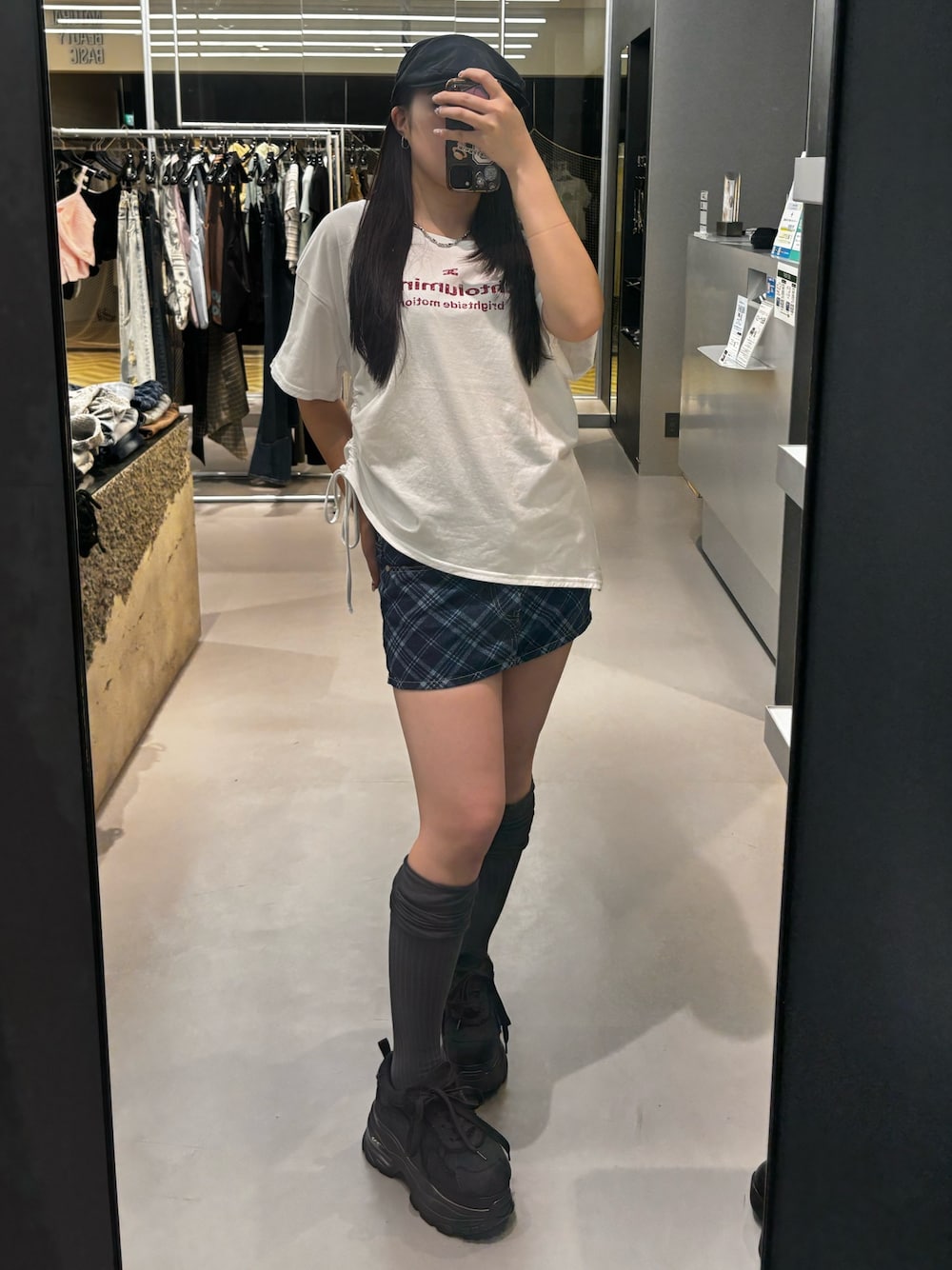 ブラック系のスニーカー、ホワイト系のTシャツ/カットソー、ブルー系のスカートを着用したレディースの春コーディネートの1枚目の写真