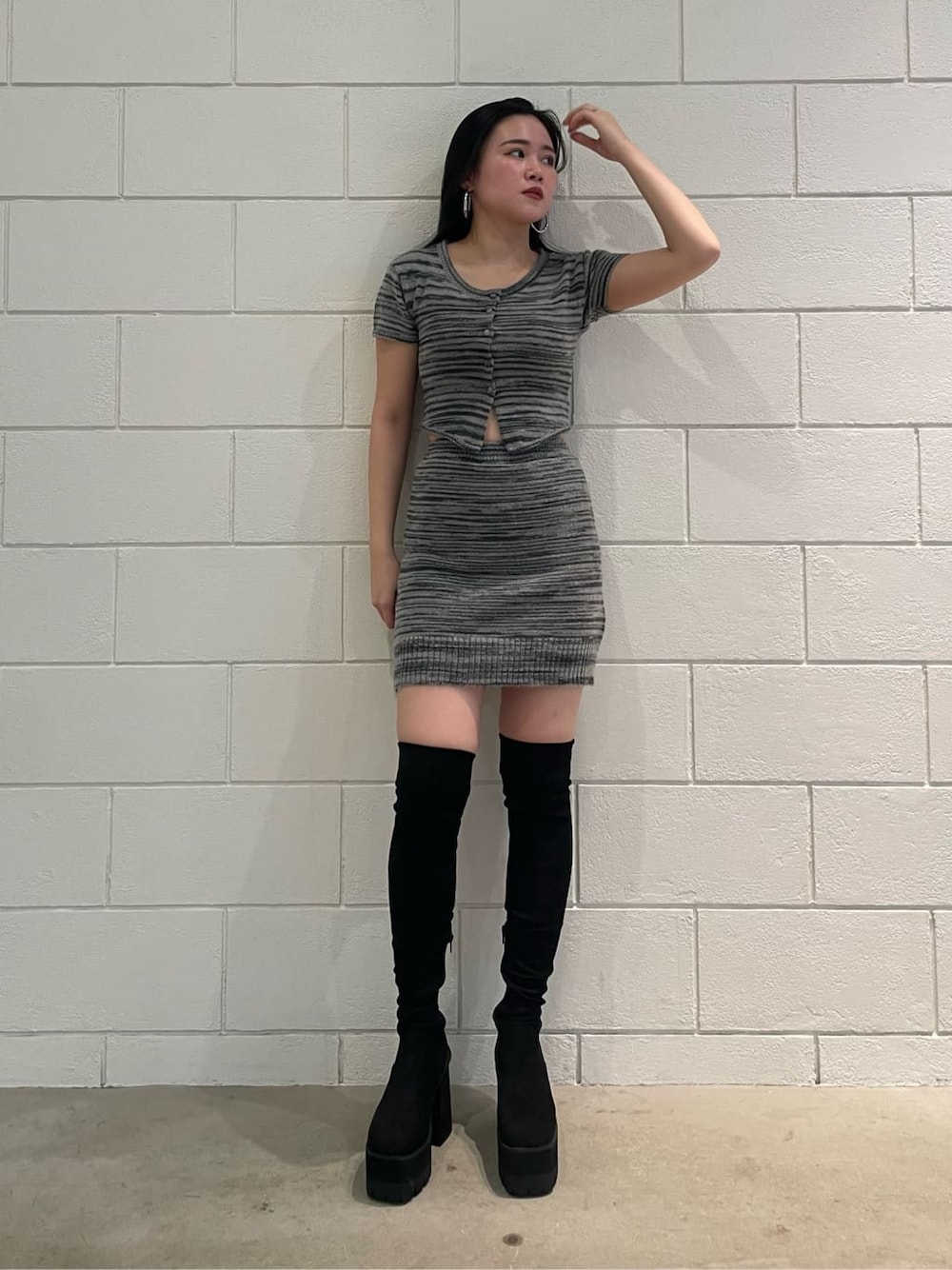 ブラック系のスカート、ブラック系のニット/セーター、ブラック系のブーツを着用したレディースの夏コーディネートの1枚目の写真