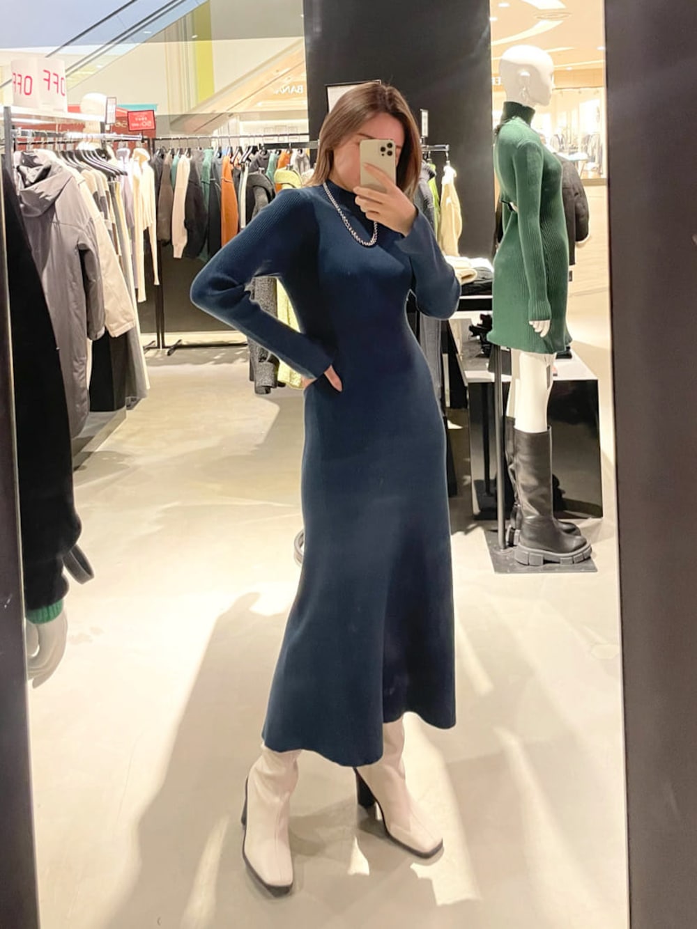 ブルー系のワンピース、ホワイト系のブーツ、シルバー系のネックレスを着用したレディースの冬コーディネートの1枚目の写真