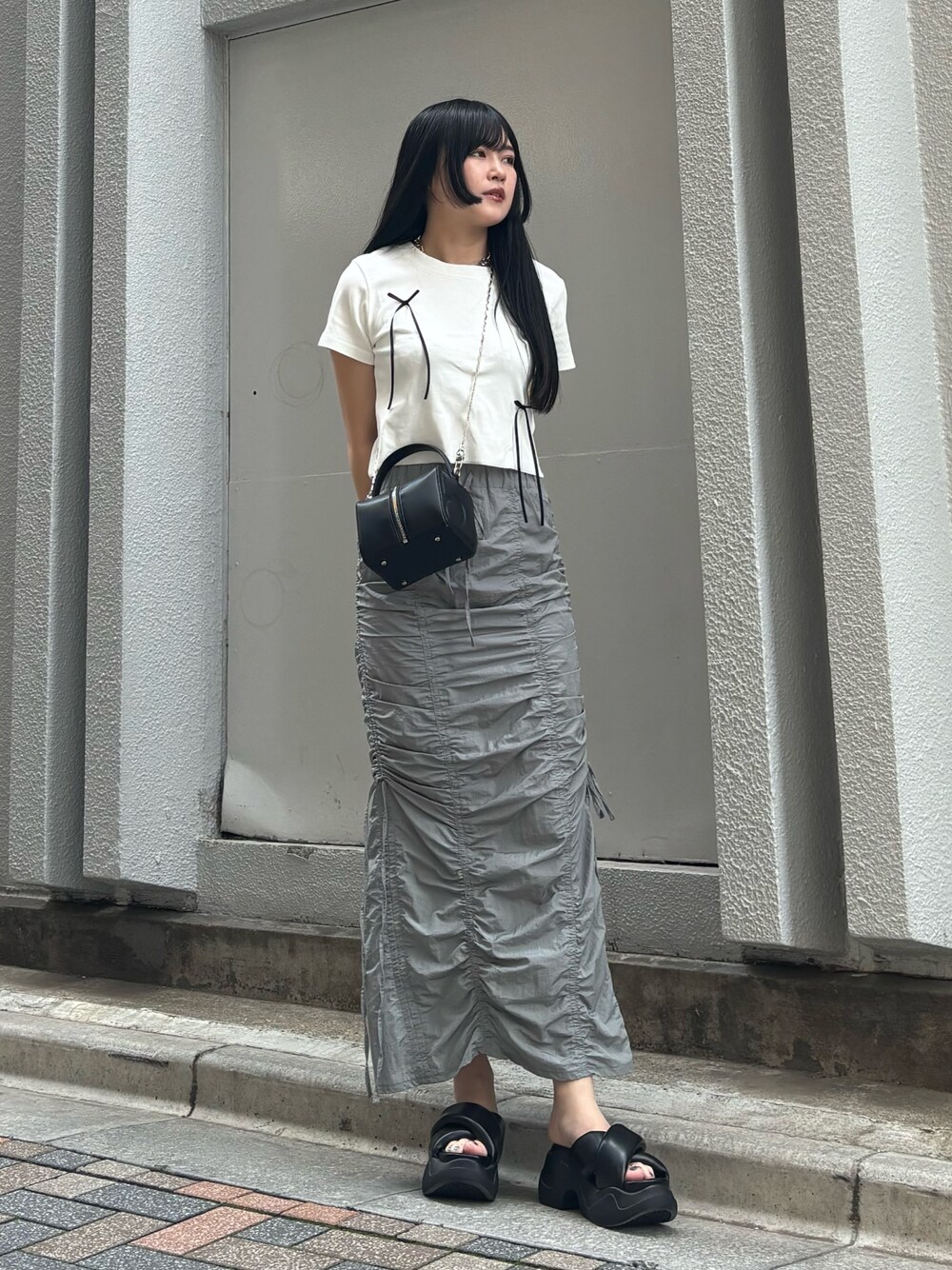 ブラック系のサンダル、ホワイト系のTシャツ/カットソー、ブラック系のハンドバッグを着用したレディースの夏コーディネートの1枚目の写真