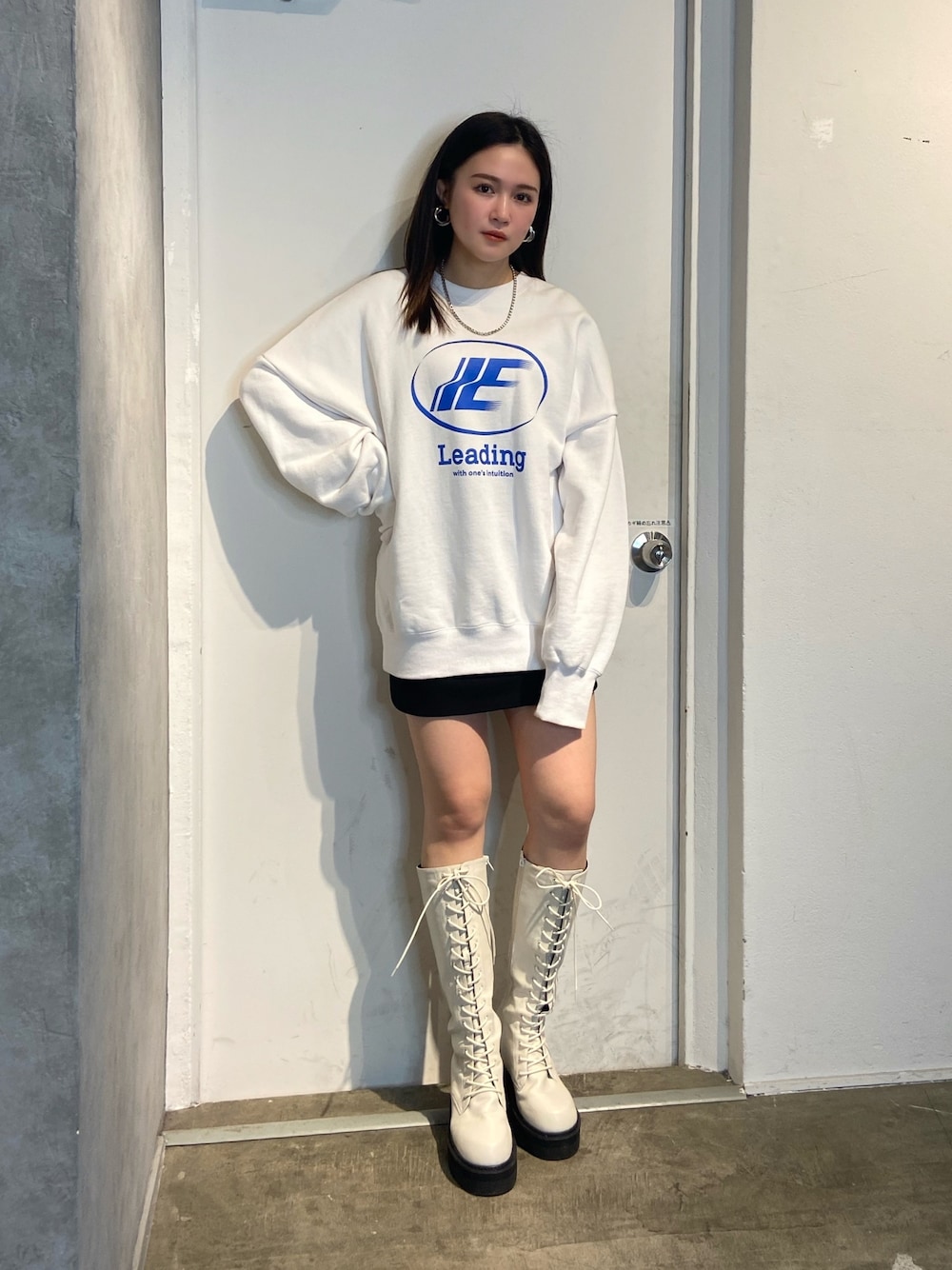 ホワイト系のスウェット、ホワイト系のブーツ、ブラック系のスカートを着用したレディースの冬コーディネートの1枚目の写真