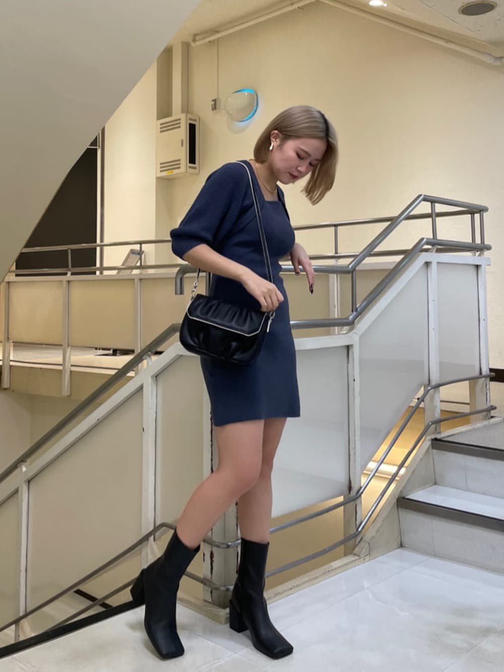 ブラック系のブーツ、ブルー系のワンピース、ブラック系のショルダーバッグを着用したレディースの秋コーディネートの1枚目の写真