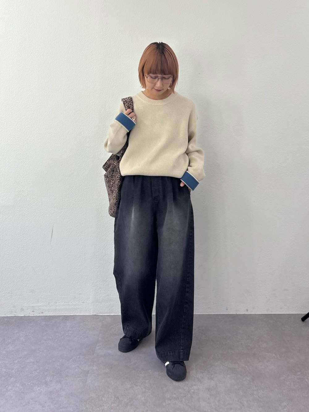 ブラック系のデニムパンツ、ホワイト系のニット/セーター、ベージュ系のトートバッグを着用したレディースの秋コーディネートの1枚目の写真