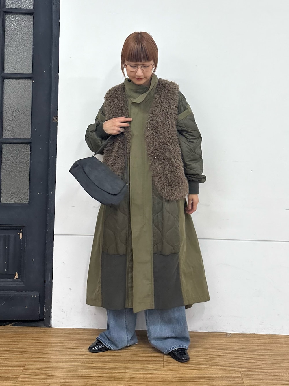 グリーン系のモッズコート、ブルー系のデニムパンツ、グレー系のハンドバッグを着用したレディースの秋コーディネートの1枚目の写真