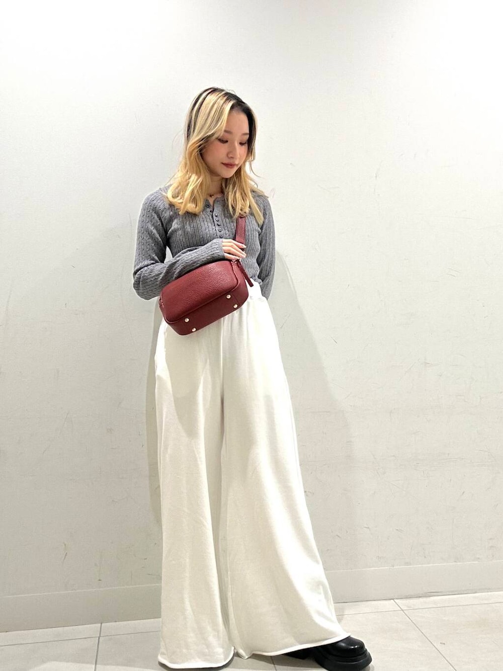 レッド系のショルダーバッグ、ブラック系のダウンジャケット/コート、ブラック系のブーツを着用したレディースの秋コーディネートの1枚目の写真