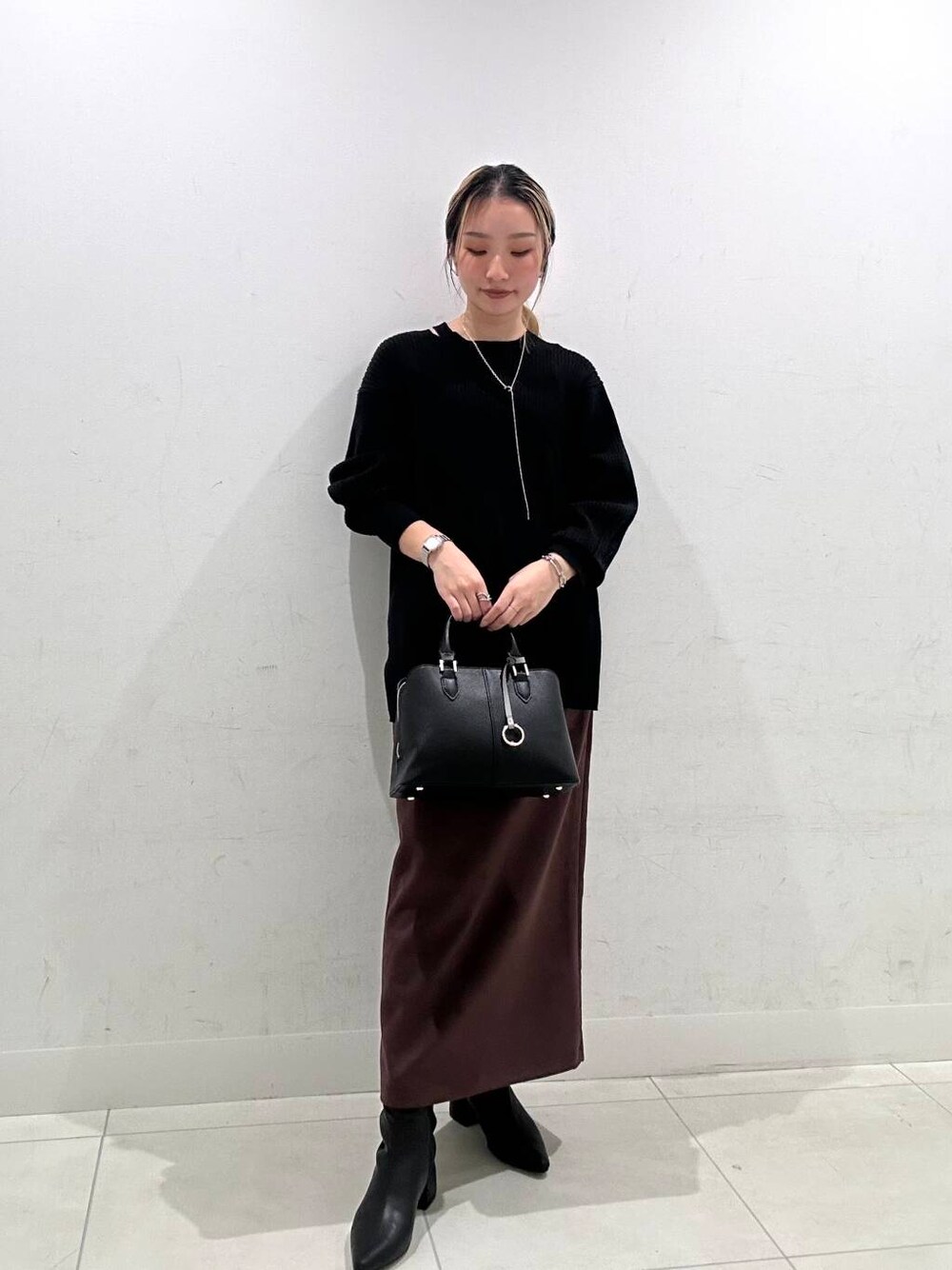 グレー系のノーカラーコート、ブラック系のハンドバッグ、ブラック系のニット/セーターを着用したレディースの冬コーディネートの1枚目の写真