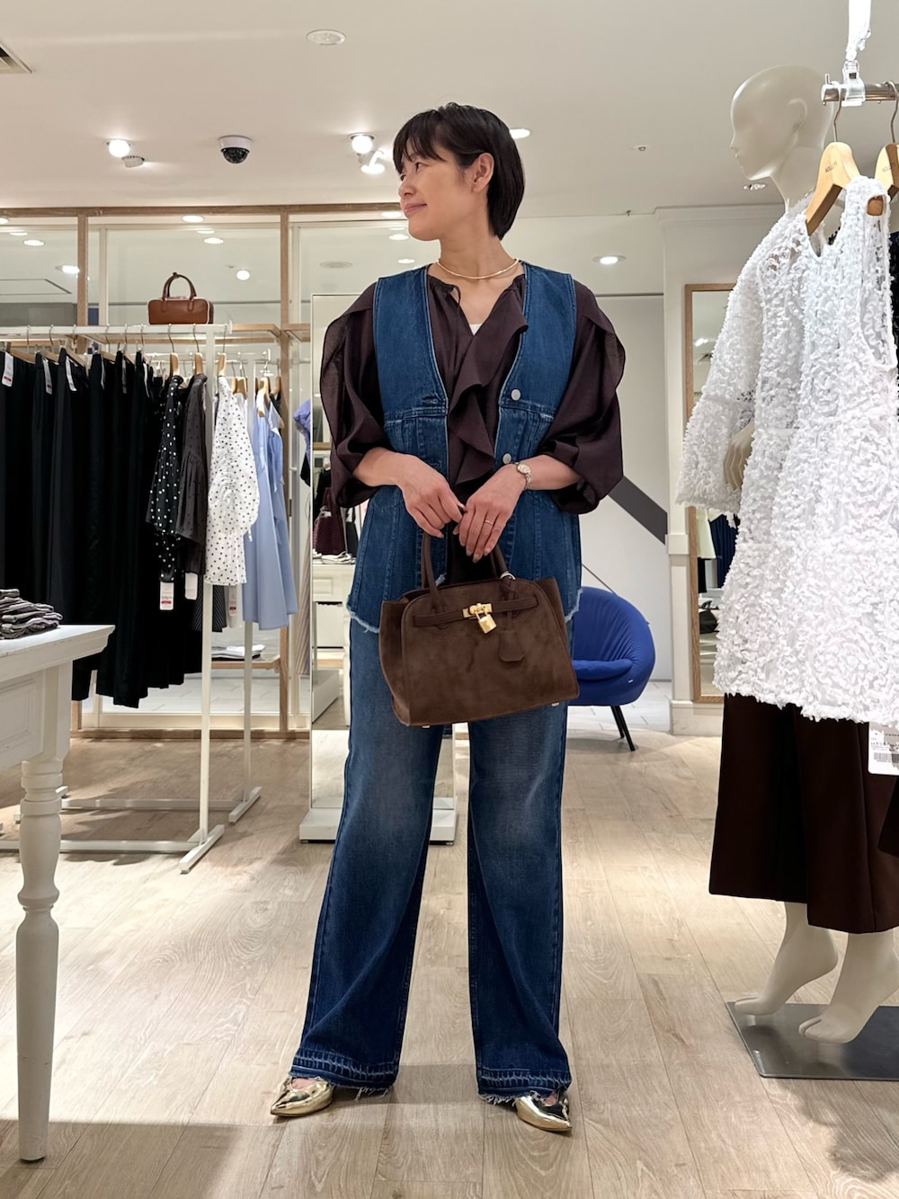 ブラウン系のシャツ/ブラウス、ブルー系のベスト、ブラウン系のトートバッグを着用したレディースの夏コーディネートの1枚目の写真