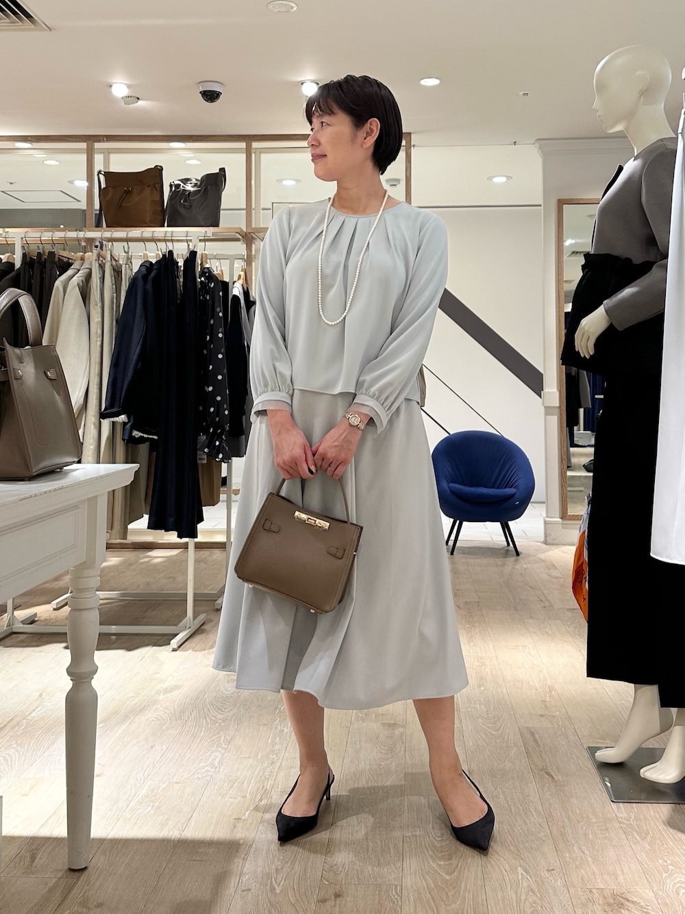 ベージュ系のショルダーバッグ、ブルー系のスカート、ブルー系のシャツ/ブラウスを着用したレディースの秋コーディネートの1枚目の写真