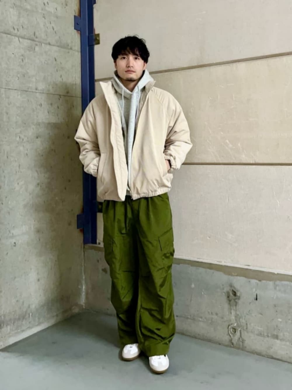 グレー系のパーカー、グリーン系のカーゴパンツ、ホワイト系のスニーカーを着用したメンズの冬コーディネートの1枚目の写真