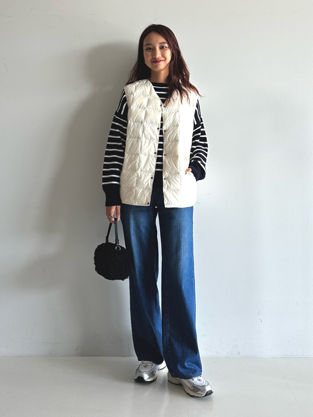 ブルー系のデニムパンツ、ブルー系のニット/セーター、ブラック系のショルダーバッグを着用したレディースの秋コーディネートの1枚目の写真