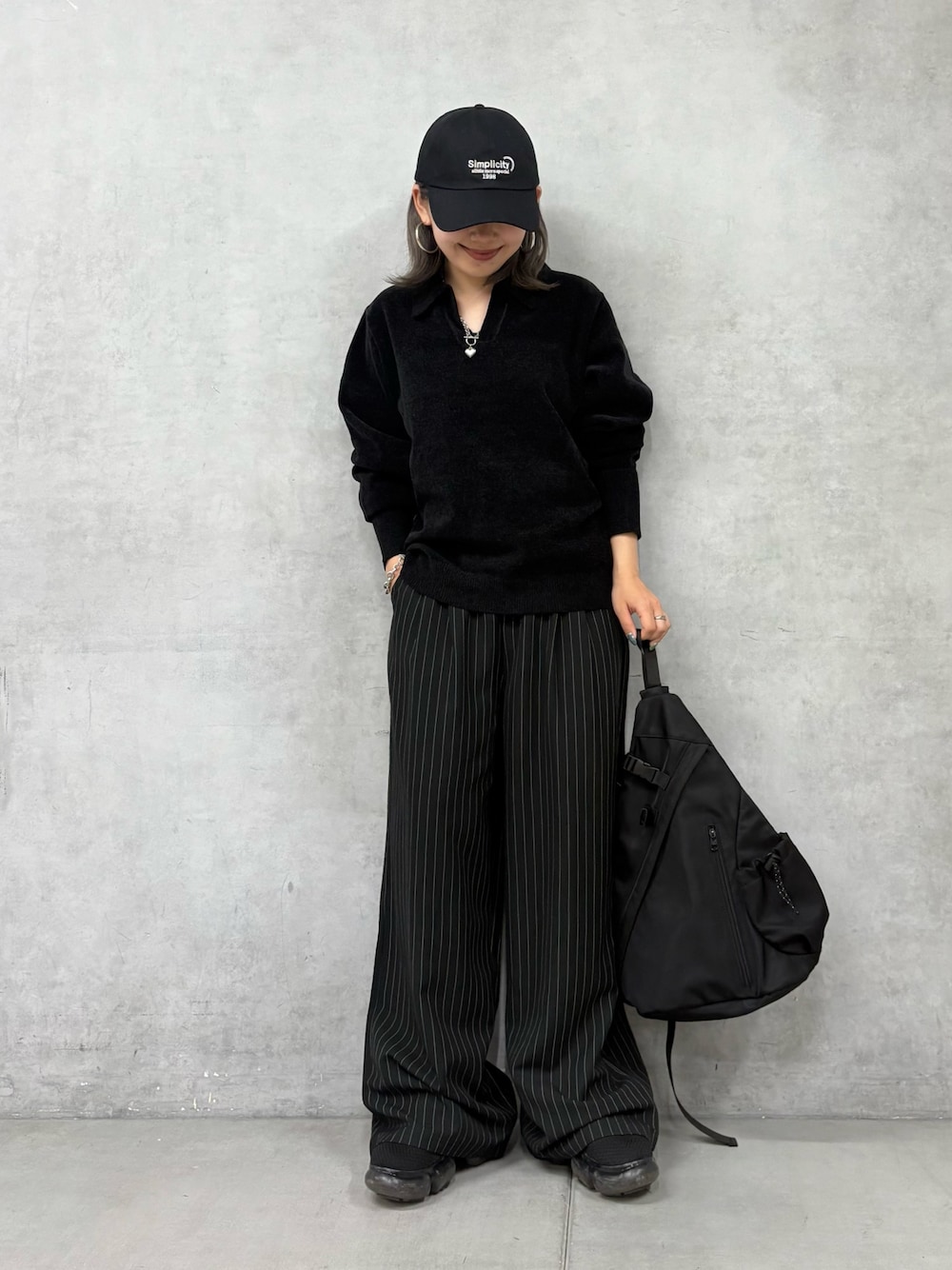 ブラック系のスラックス、ブラック系のボディバッグ/ウエストポーチ、ブラック系のニット/セーターを着用したレディースの秋コーディネートの1枚目の写真