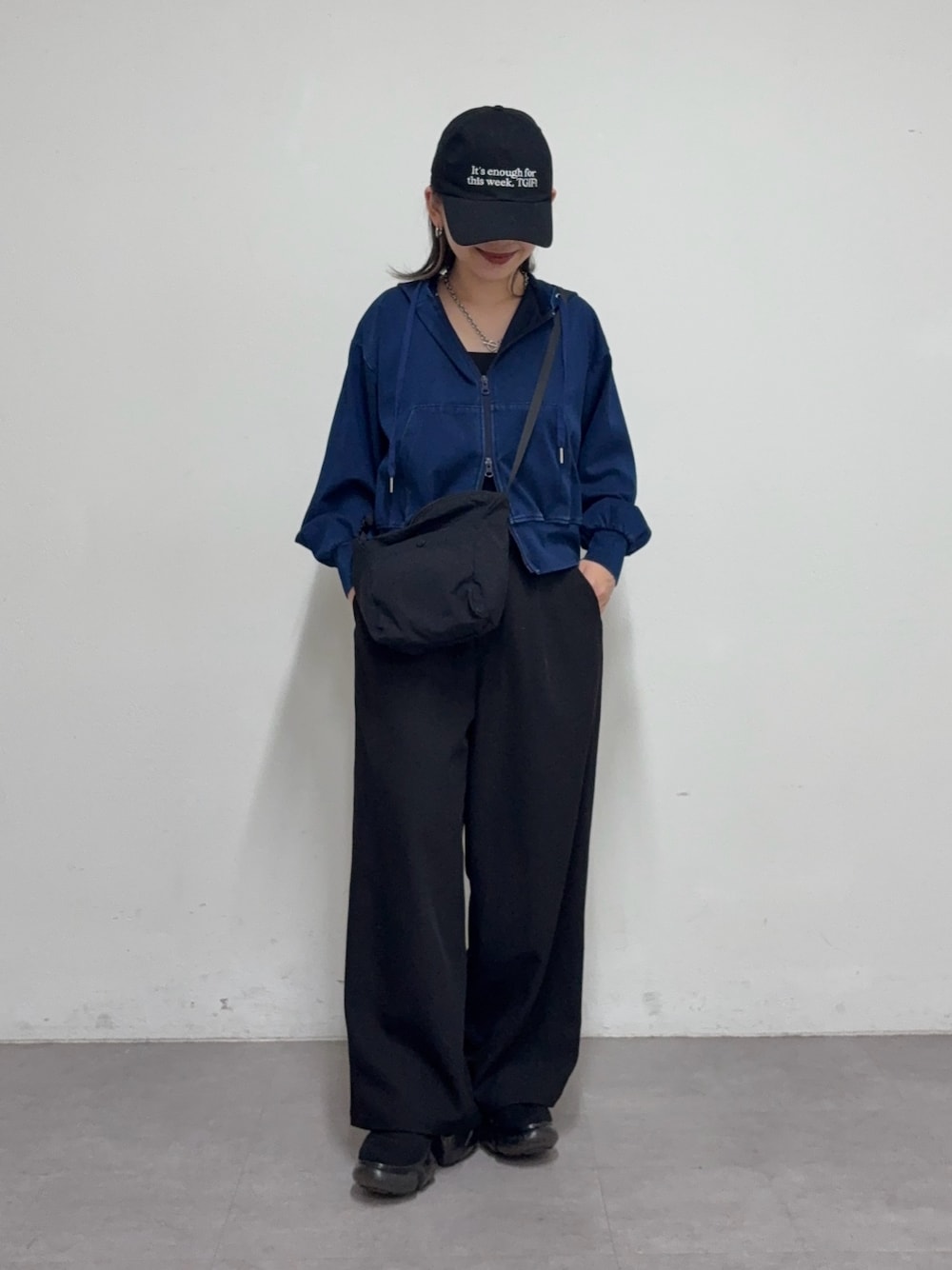 ブラック系のスラックス、ブラック系のショルダーバッグ、ブルー系のパーカーを着用したレディースの冬コーディネートの1枚目の写真