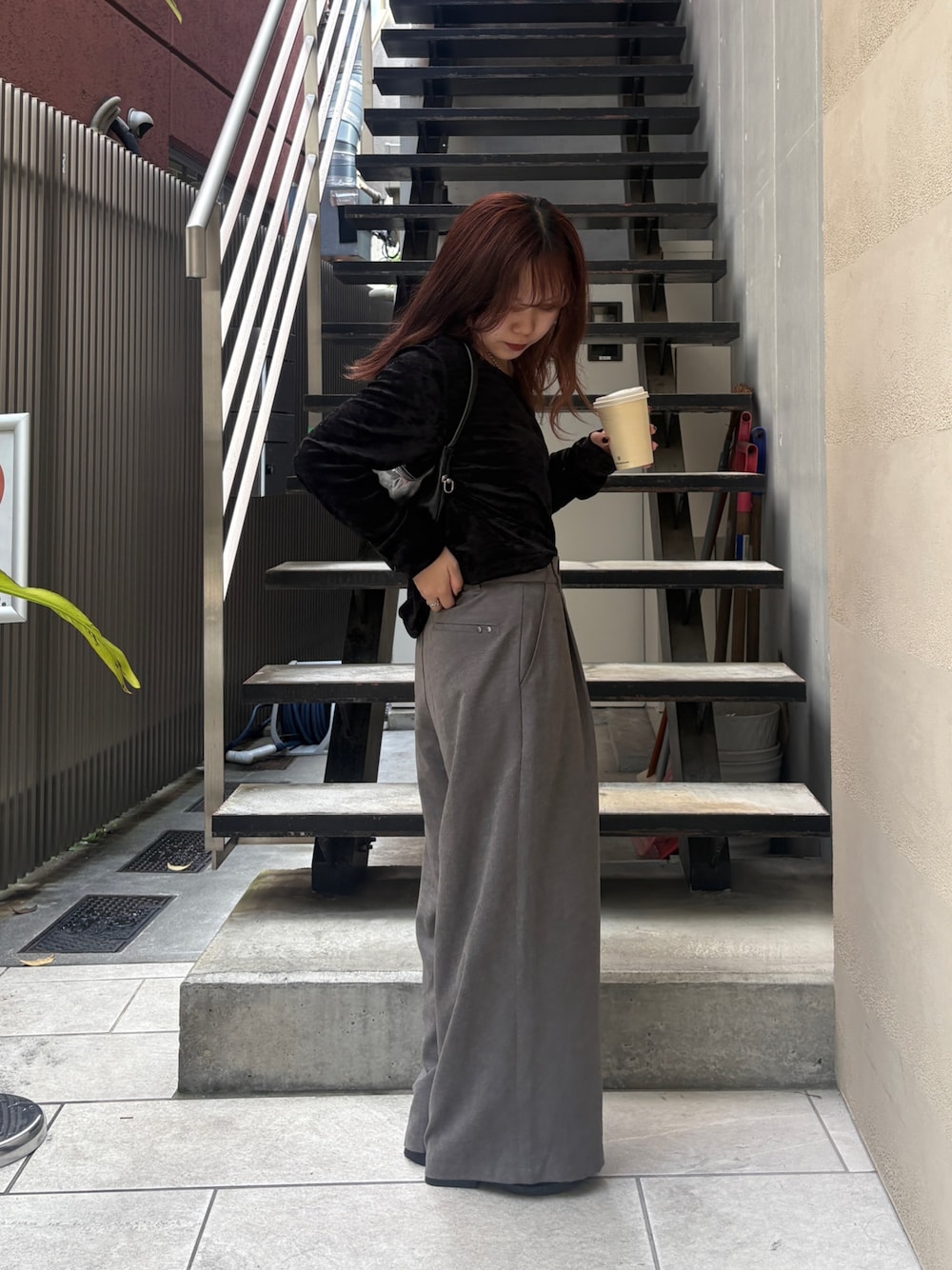グレー系のスラックス、ブラック系のトートバッグ、ブラック系のTシャツ/カットソーを着用したレディースの夏コーディネートの1枚目の写真