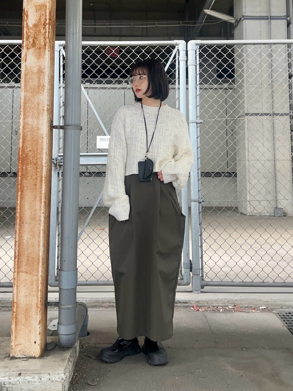 ホワイト系のニット/セーター、グリーン系のスカート、ブラック系のショルダーバッグを着用したレディースの冬コーディネートの1枚目の写真