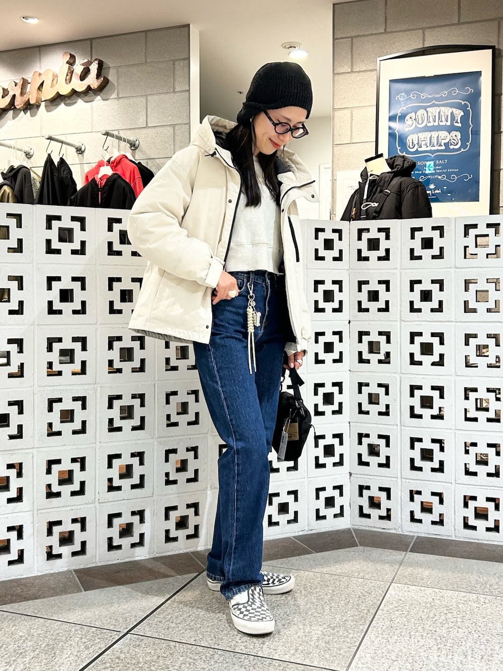 ブラック系のショルダーバッグ、ホワイト系のダウンジャケット/コート、ブルー系のデニムパンツを着用したレディースの冬コーディネートの1枚目の写真