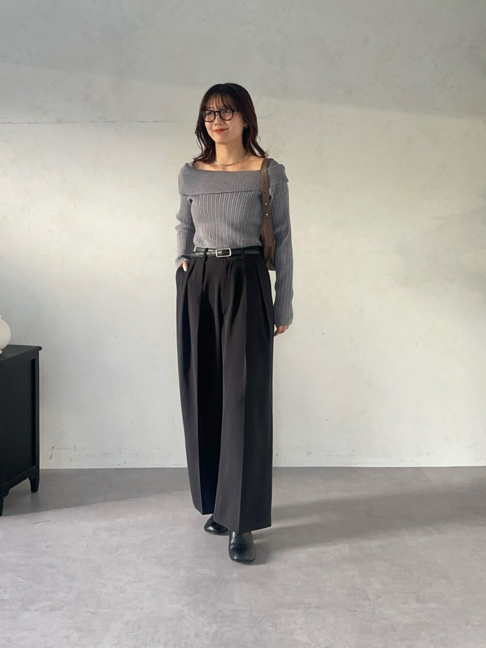 ブラック系のスラックス、グレー系のニット/セーター、ブラック系のベルトを着用したレディースの秋コーディネートの1枚目の写真