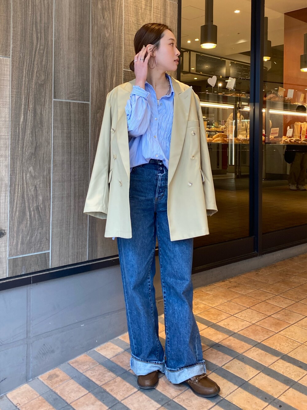 ベージュ系のテーラードジャケット、ブルー系のデニムパンツ、ブラウン系のローファーを着用したレディースの冬コーディネートの1枚目の写真