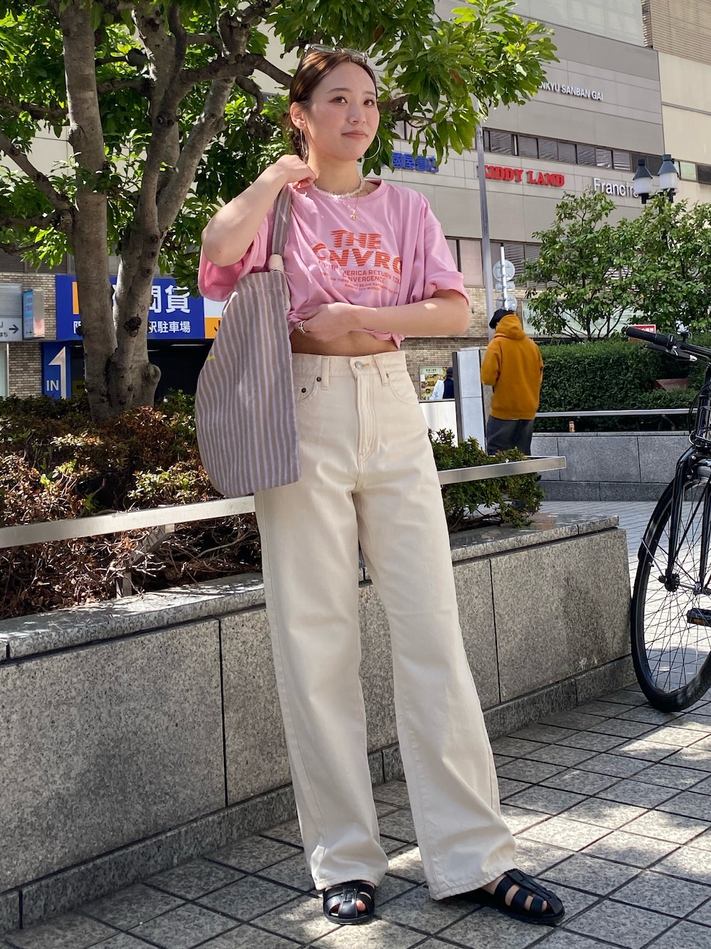 ホワイト系のデニムパンツ、ピンク系のTシャツ/カットソー、ブラック系のサンダルを着用したレディースの春コーディネートの1枚目の写真