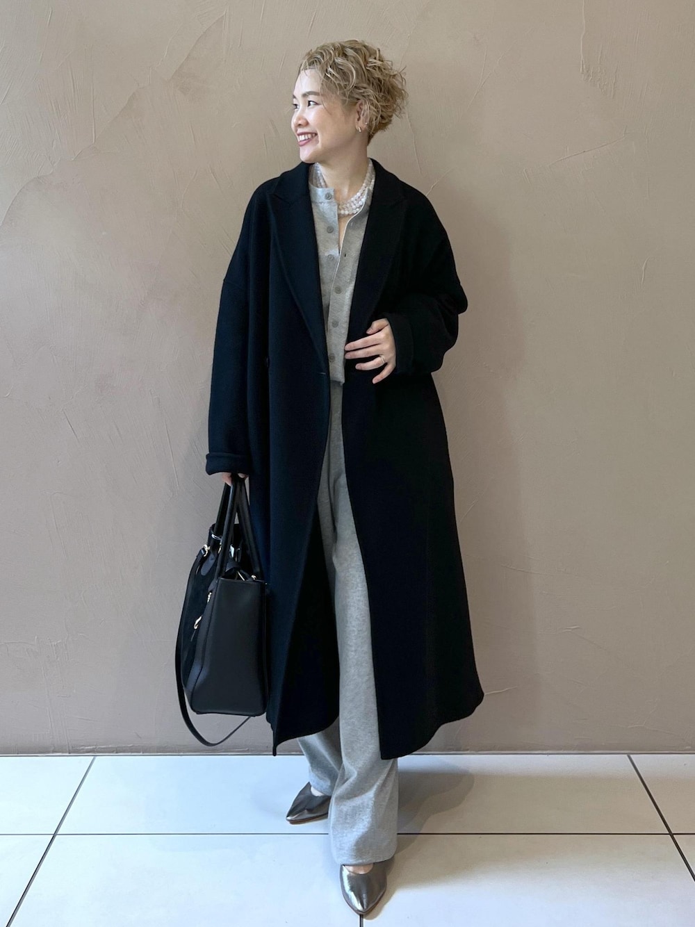 ブラック系のハンドバッグ、ブラック系のその他アウター、シルバー系のパンプスを着用したレディースの秋コーディネートの1枚目の写真