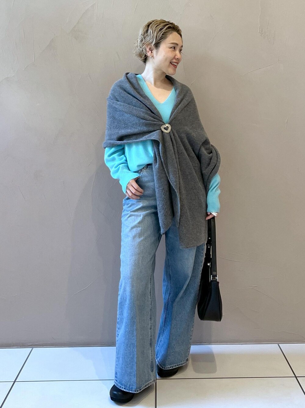 ブルー系のニット/セーター、ブルー系のデニムパンツ、ブラック系のスニーカーを着用したレディースの秋コーディネートの1枚目の写真