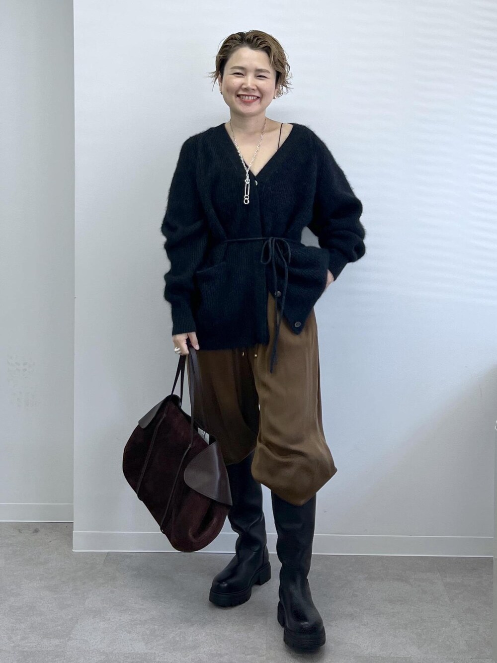ブラック系のブーツ、ブラウン系のその他パンツ、グレー系のカーディガン/ボレロを着用したレディースの秋コーディネートの1枚目の写真