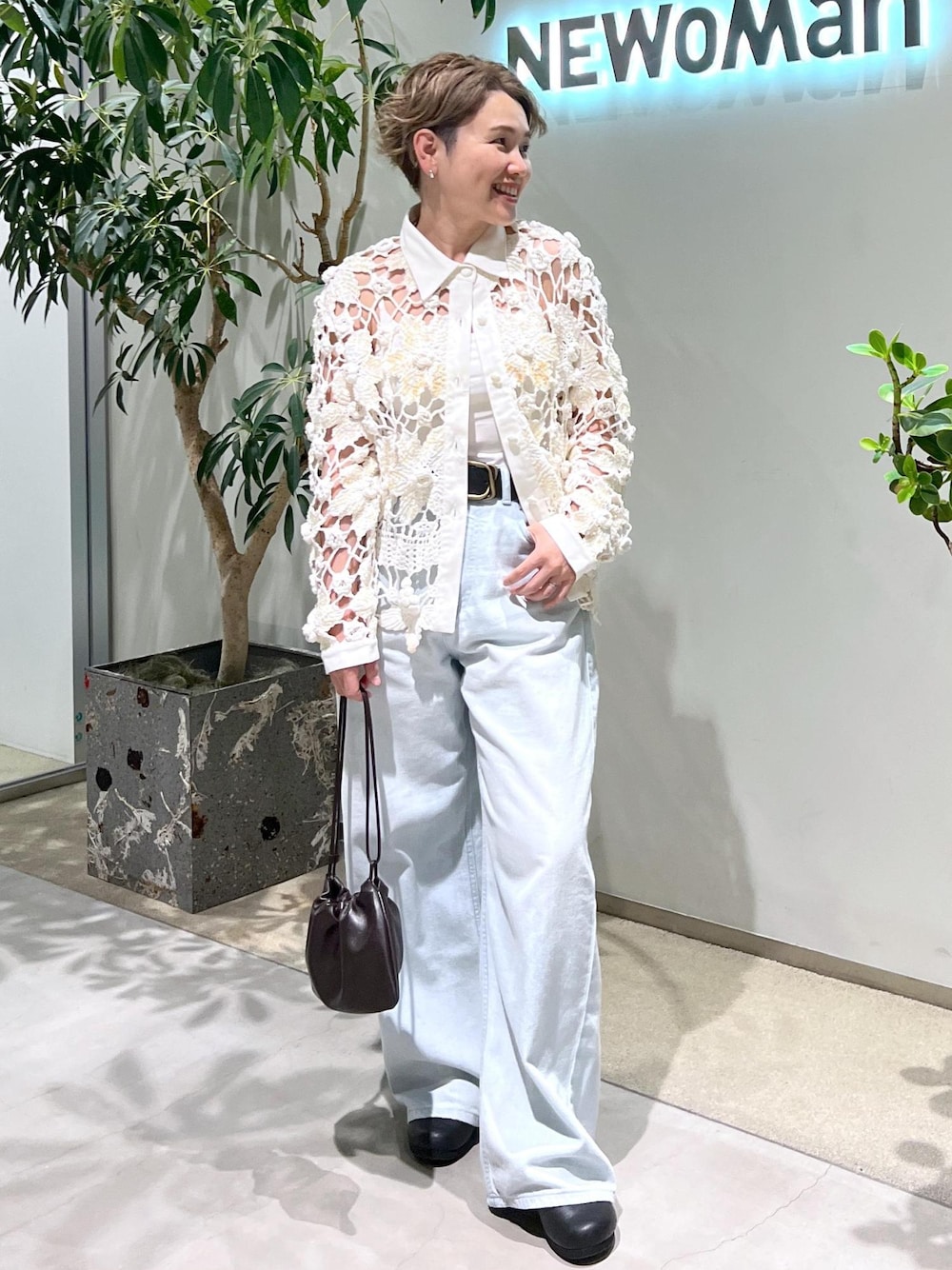 ブルー系のデニムパンツ、ブラウン系のハンドバッグを着用したレディースの夏コーディネートの1枚目の写真