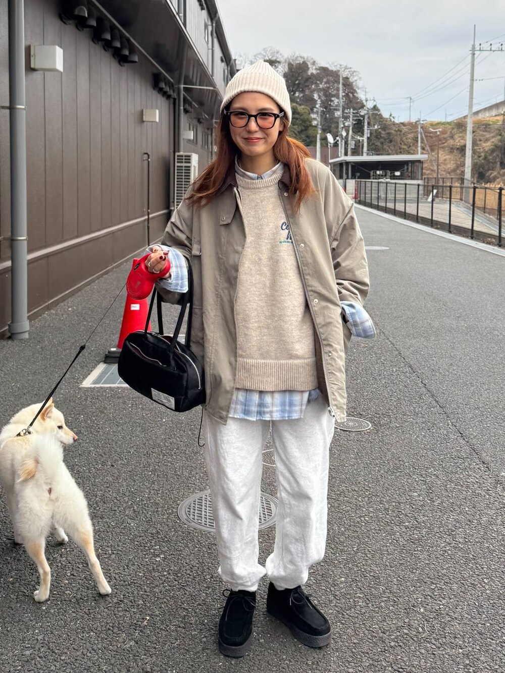 グレー系のスウェットパンツ、ベージュ系のニット/セーター、ブラック系のボストンバッグを着用したレディースの冬コーディネートの1枚目の写真