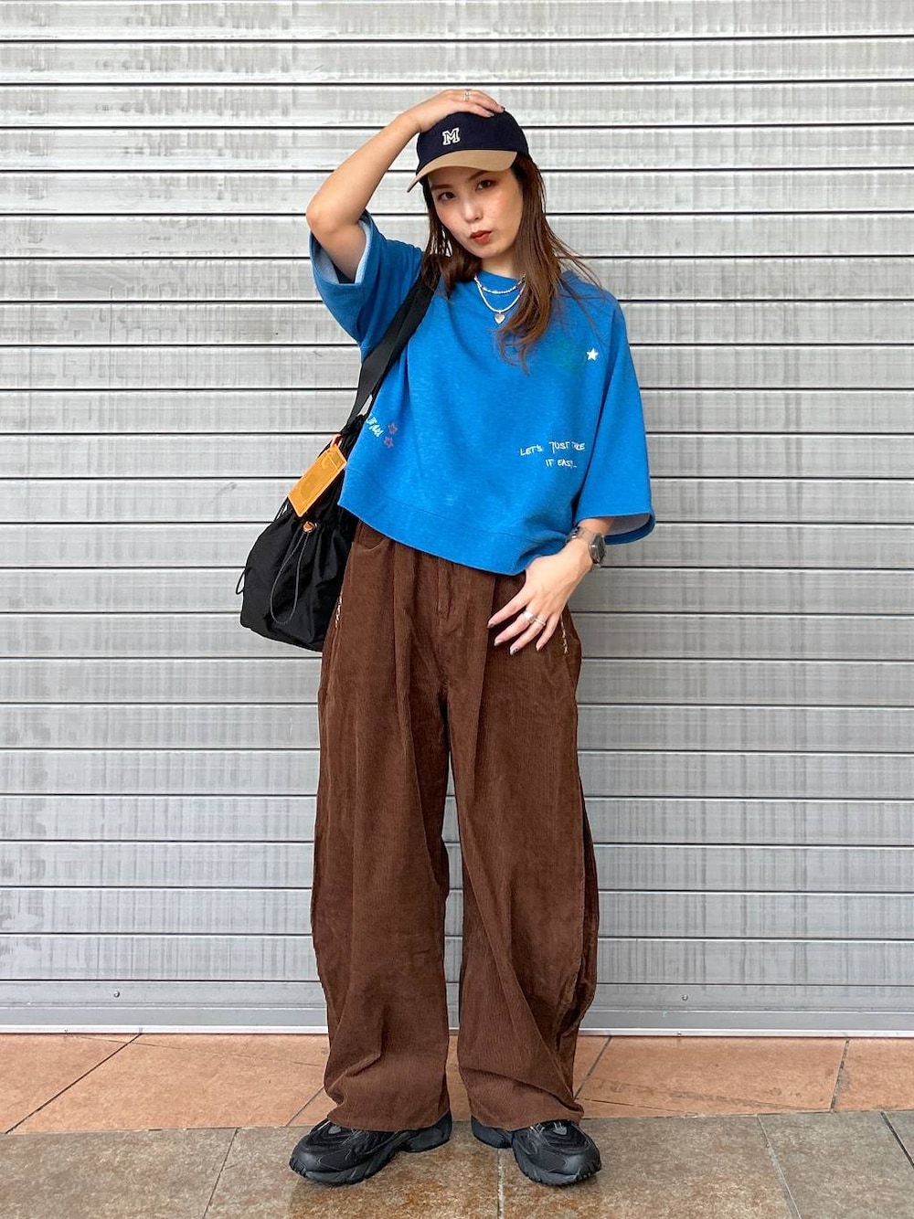 ブラック系のスニーカー、ブルー系のTシャツ/カットソー、ブラック系のトートバッグを着用したレディースの秋コーディネートの1枚目の写真