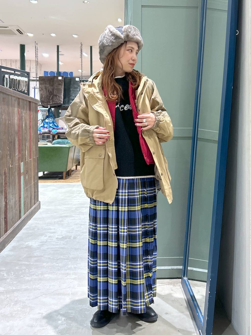 ブルー系のスカート、ベージュ系のマウンテンパーカー、ブラック系のニット/セーターを着用したレディースの冬コーディネートの1枚目の写真