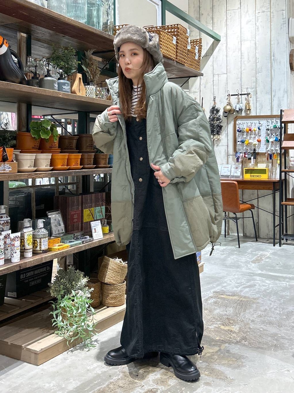 グリーン系のブルゾン、ブラック系のブーツ、ホワイト系のTシャツ/カットソーを着用したレディースの冬コーディネートの1枚目の写真