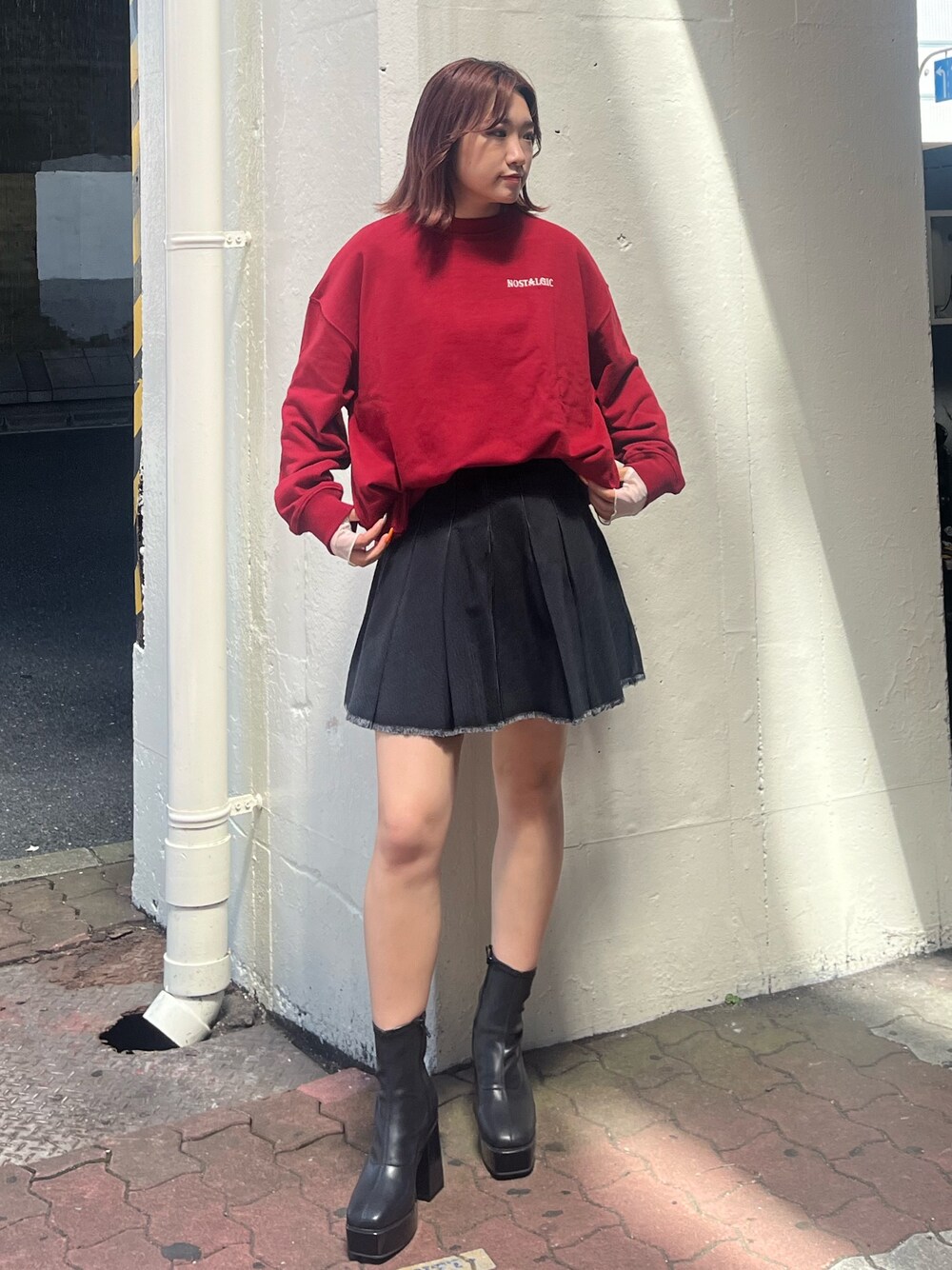 ブラック系のデニムスカート、レッド系のスウェット、ブラック系のブーツを着用したレディースの秋コーディネートの1枚目の写真