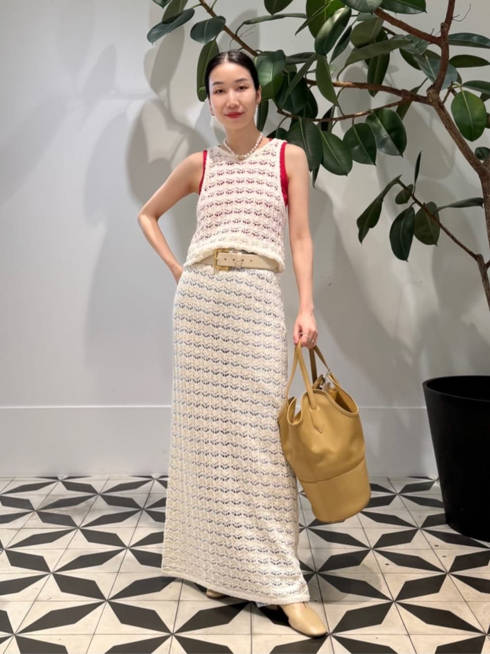 ブルー系のデニムパンツ、ベージュ系のパンプス、レッド系のタンクトップを着用したレディースの夏コーディネートの1枚目の写真