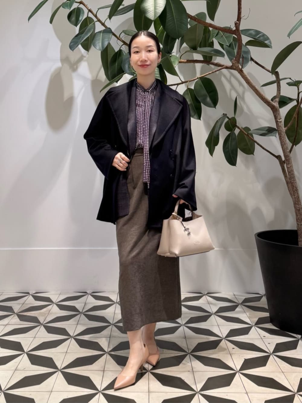 ブラック系のキャミソール、ブルー系のピーコート、ブラウン系のテーラードジャケットを着用したレディースの冬コーディネートの1枚目の写真