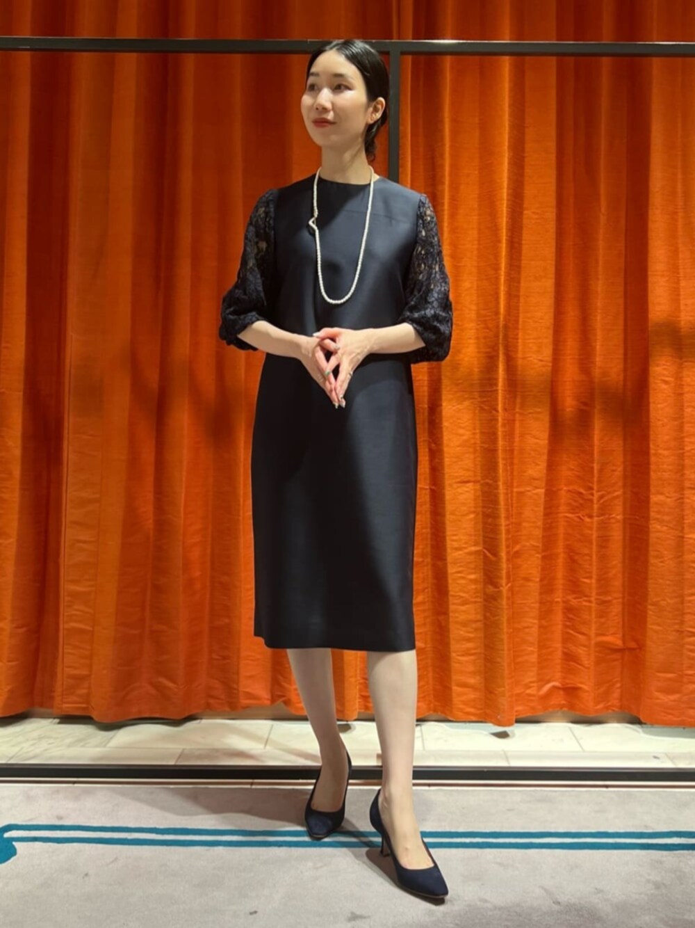 ブルー系のパンプス、ブルー系のワンピース、ホワイト系のネックレスを着用したレディースの春コーディネートの1枚目の写真