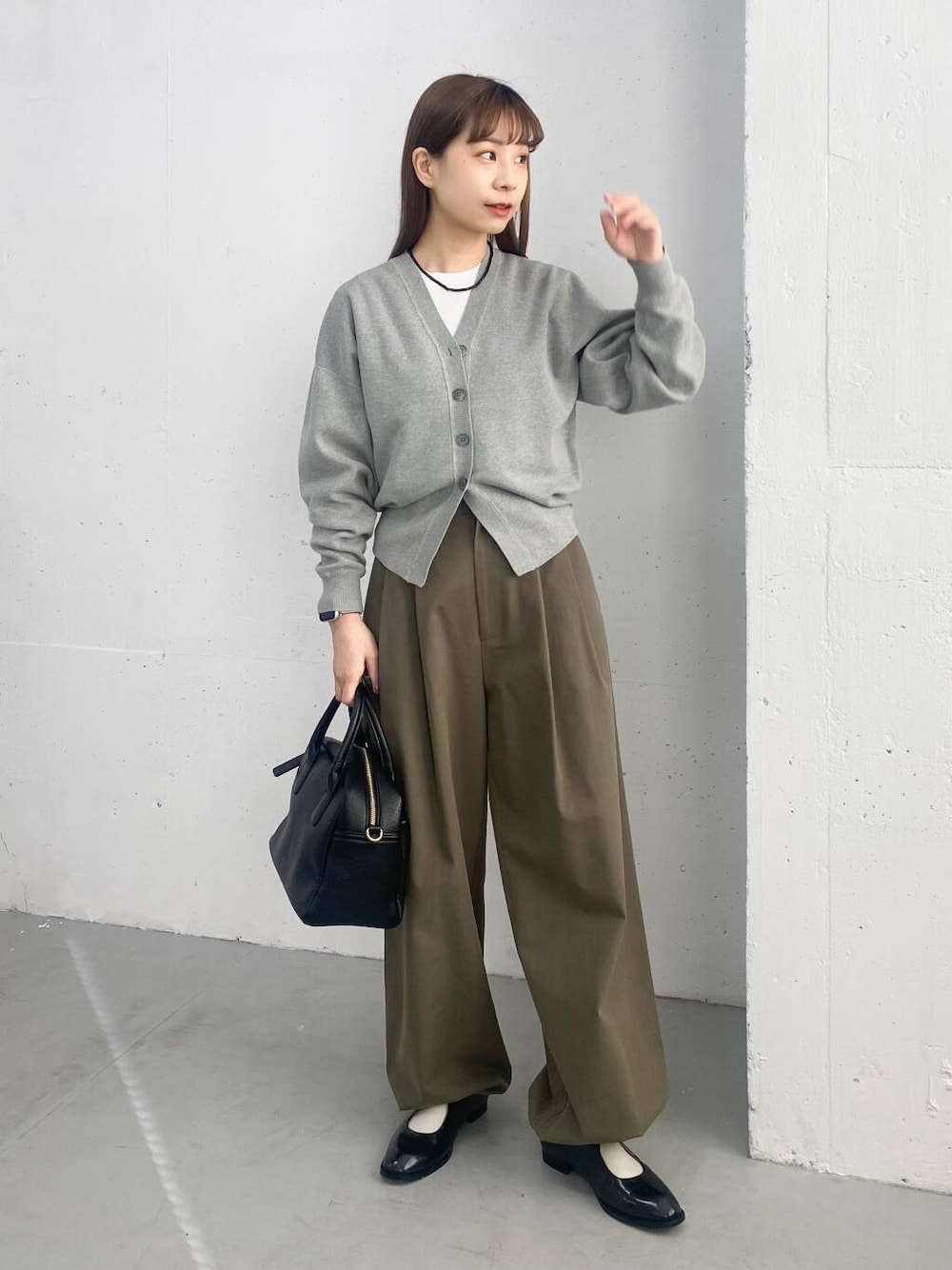 ブラック系のボストンバッグ、ブラック系のローファー、グレー系のカーディガン/ボレロを着用したレディースの春コーディネートの1枚目の写真