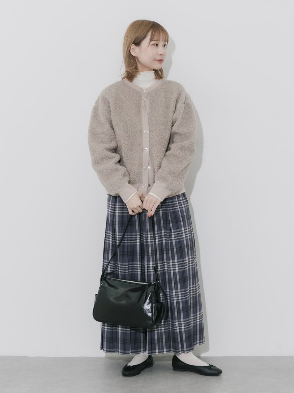 グレー系のスカート、ベージュ系のカーディガン/ボレロ、ブラック系のショルダーバッグを着用したレディースの秋コーディネートの1枚目の写真
