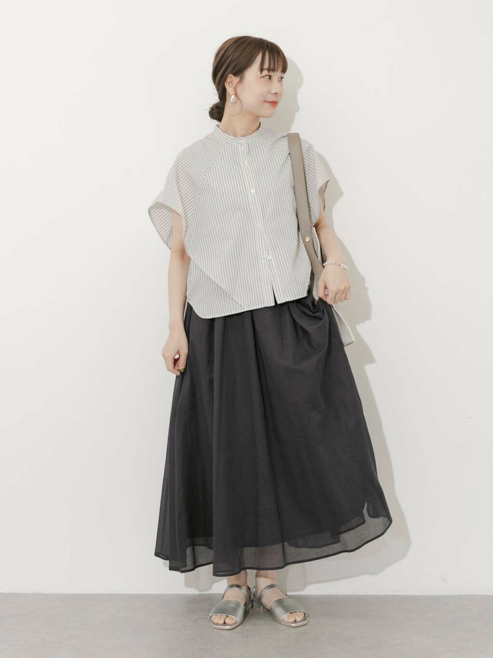 グレー系のスカート、ホワイト系のシャツ/ブラウス、シルバー系のサンダルを着用したレディースの夏コーディネートの1枚目の写真