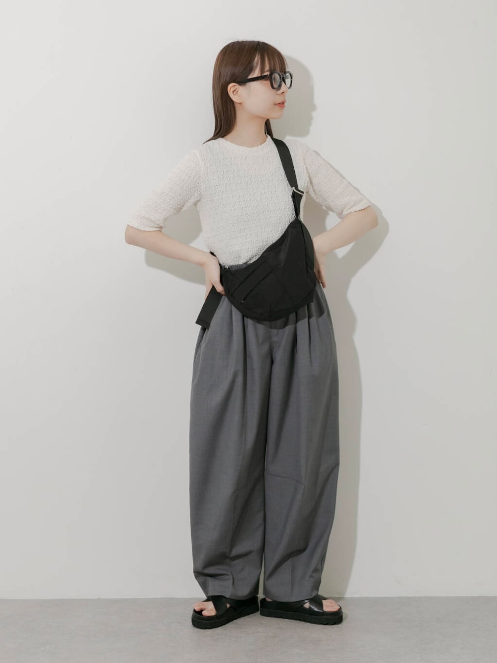 グレー系のその他パンツ、ホワイト系のTシャツ/カットソー、ブラック系のサンダルを着用したレディースの春コーディネートの1枚目の写真