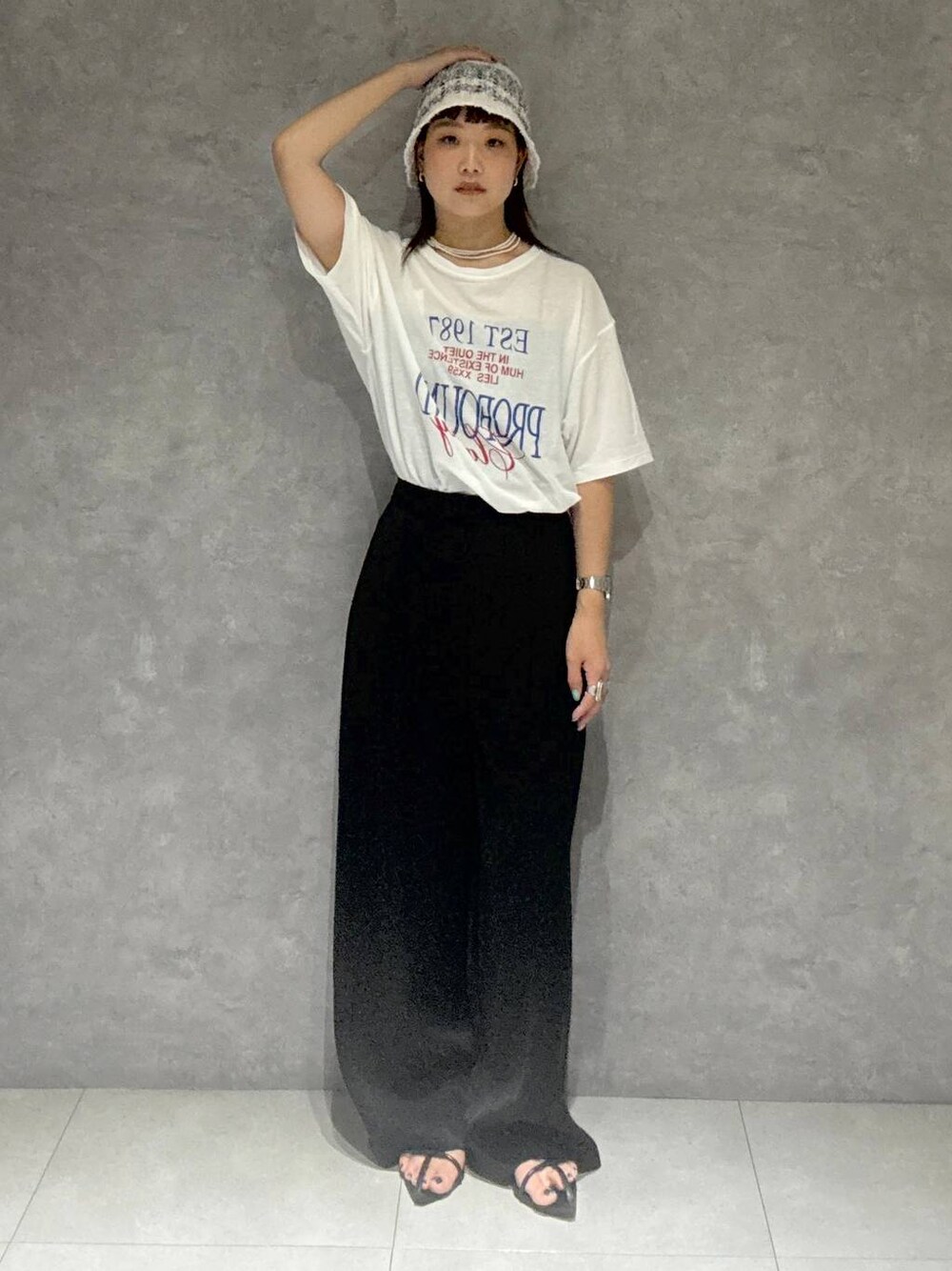 ブラック系のサンダル、ブラック系のスラックス、ホワイト系のTシャツ/カットソーを着用したレディースの夏コーディネートの1枚目の写真