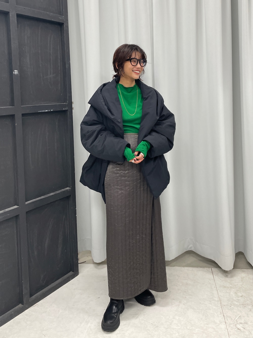 ブラック系のダウンジャケット/コート、グリーン系のTシャツ/カットソー、グリーン系のスカートを着用したレディースの秋コーディネートの1枚目の写真
