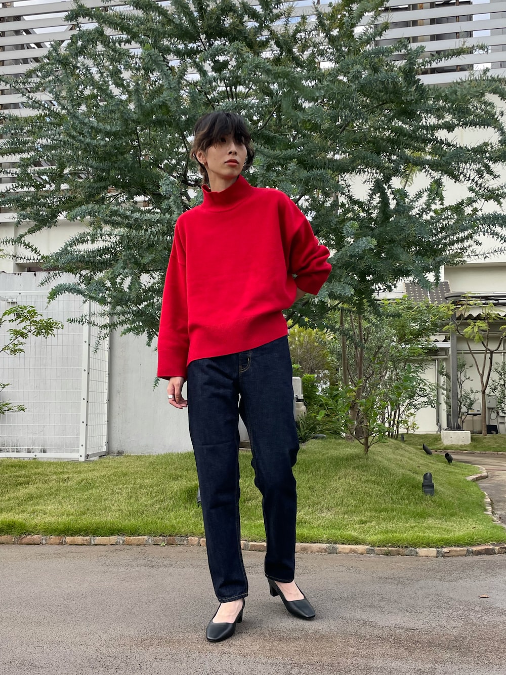 レッド系のニット/セーター、ブルー系のデニムパンツを着用したレディースの秋コーディネートの1枚目の写真