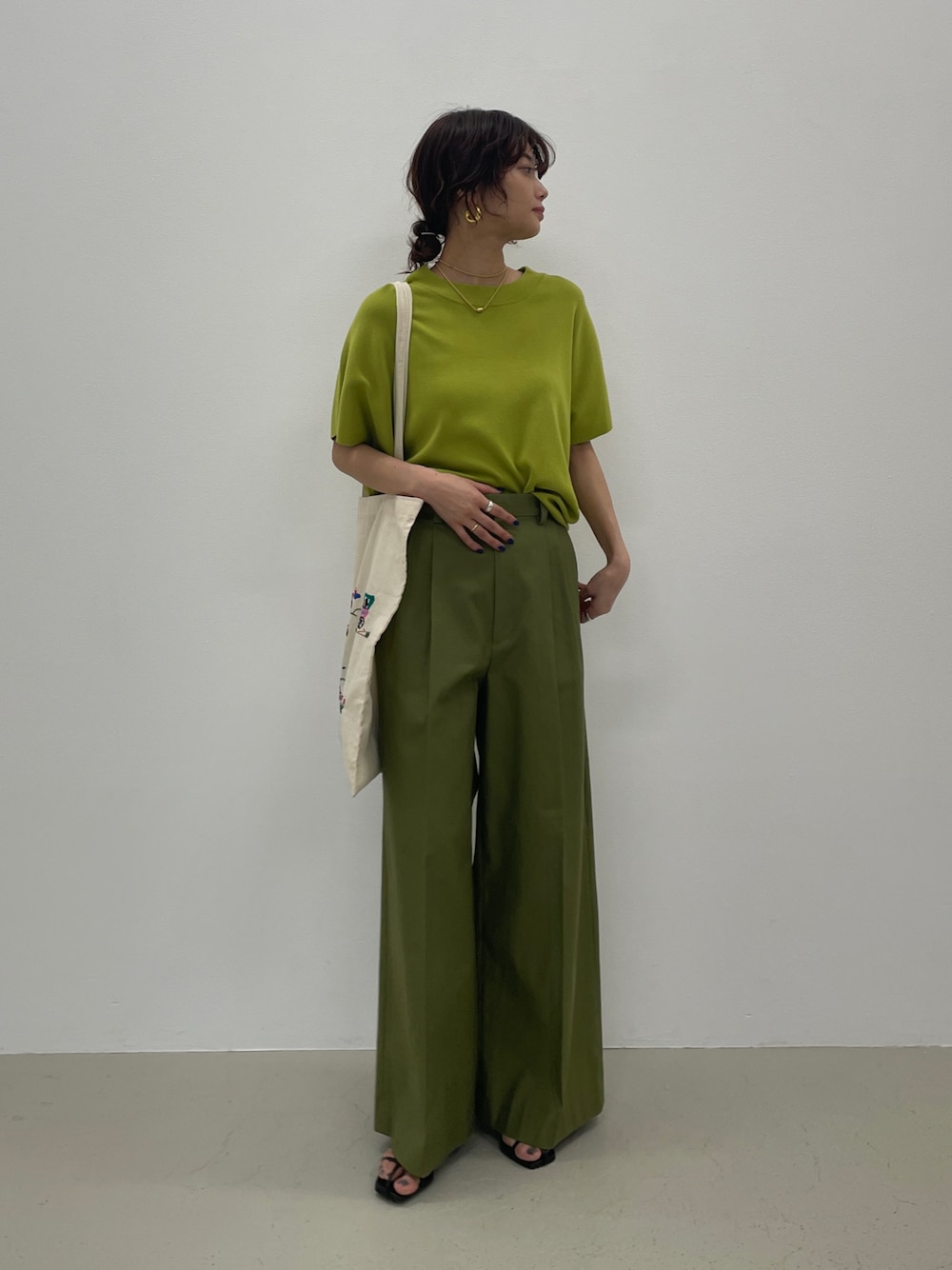 グリーン系のチノパンツ、ホワイト系のトートバッグ、グリーン系のニット/セーターを着用したレディースの春コーディネートの1枚目の写真