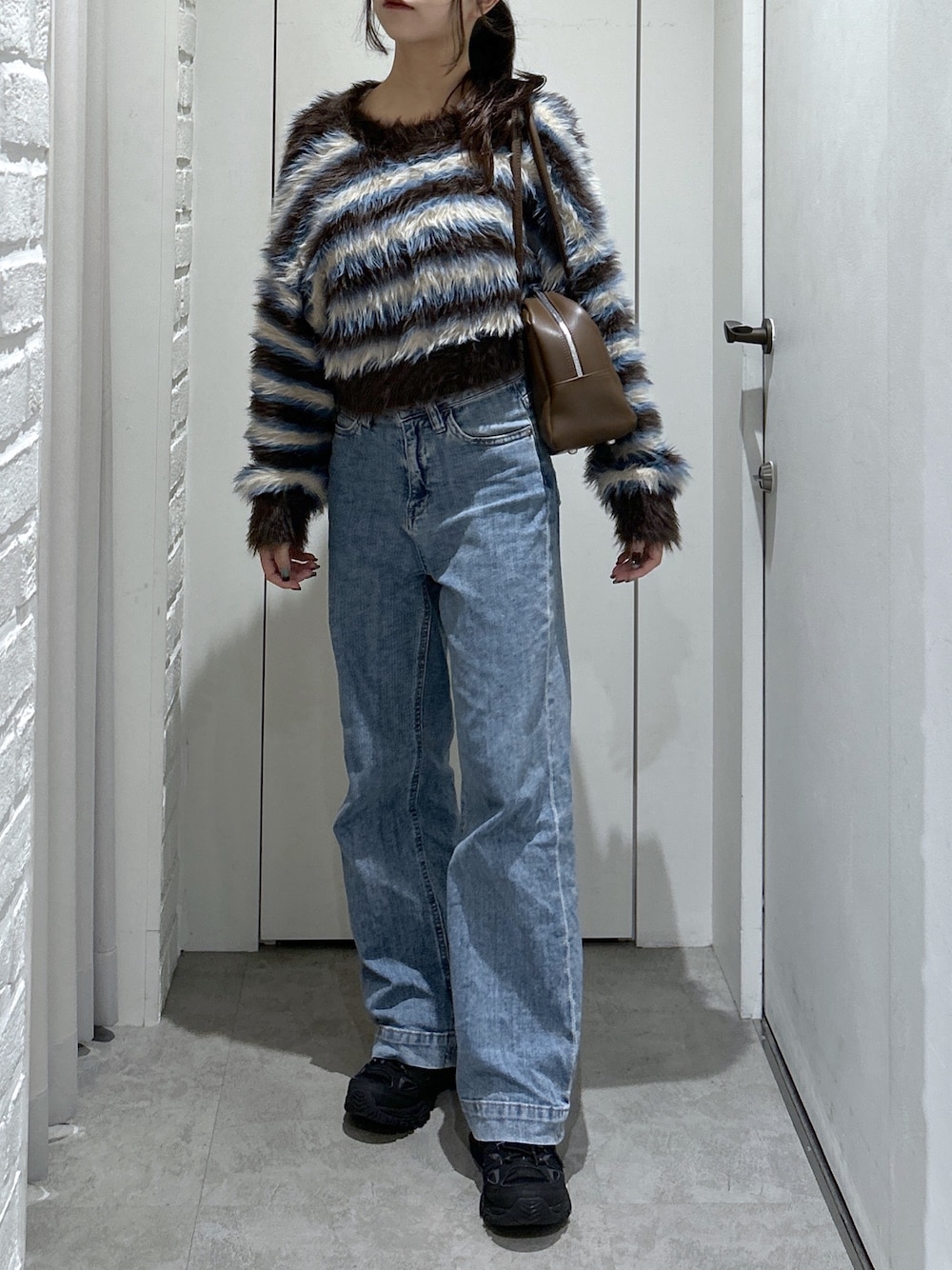 ブルー系のデニムパンツ、ブラウン系のトートバッグ、ブラウン系のニット/セーターを着用したレディースの秋コーディネートの1枚目の写真