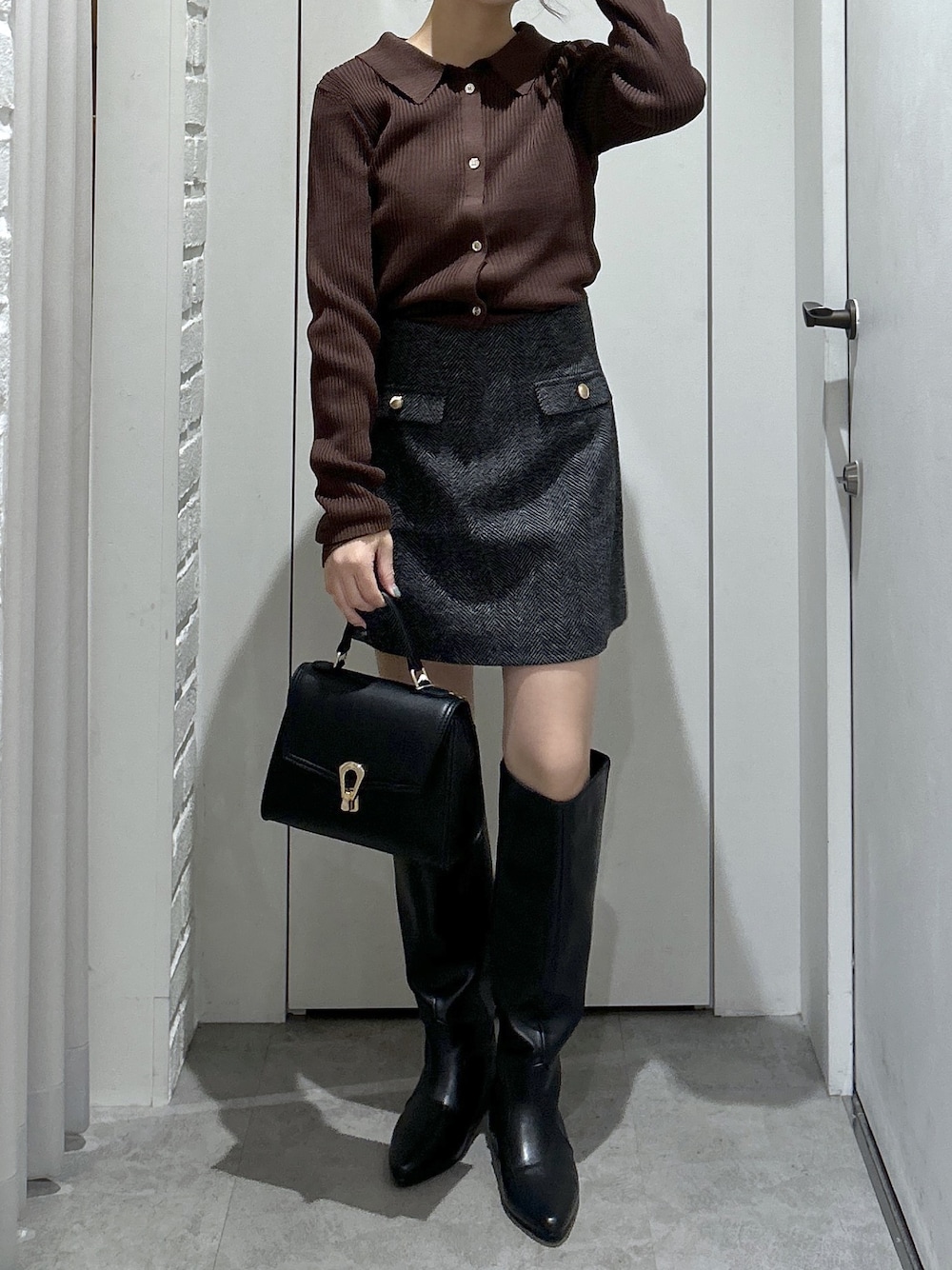 ブラウン系のニット/セーター、ブラック系のスカート、ブラック系のブーツを着用したレディースの秋コーディネートの1枚目の写真