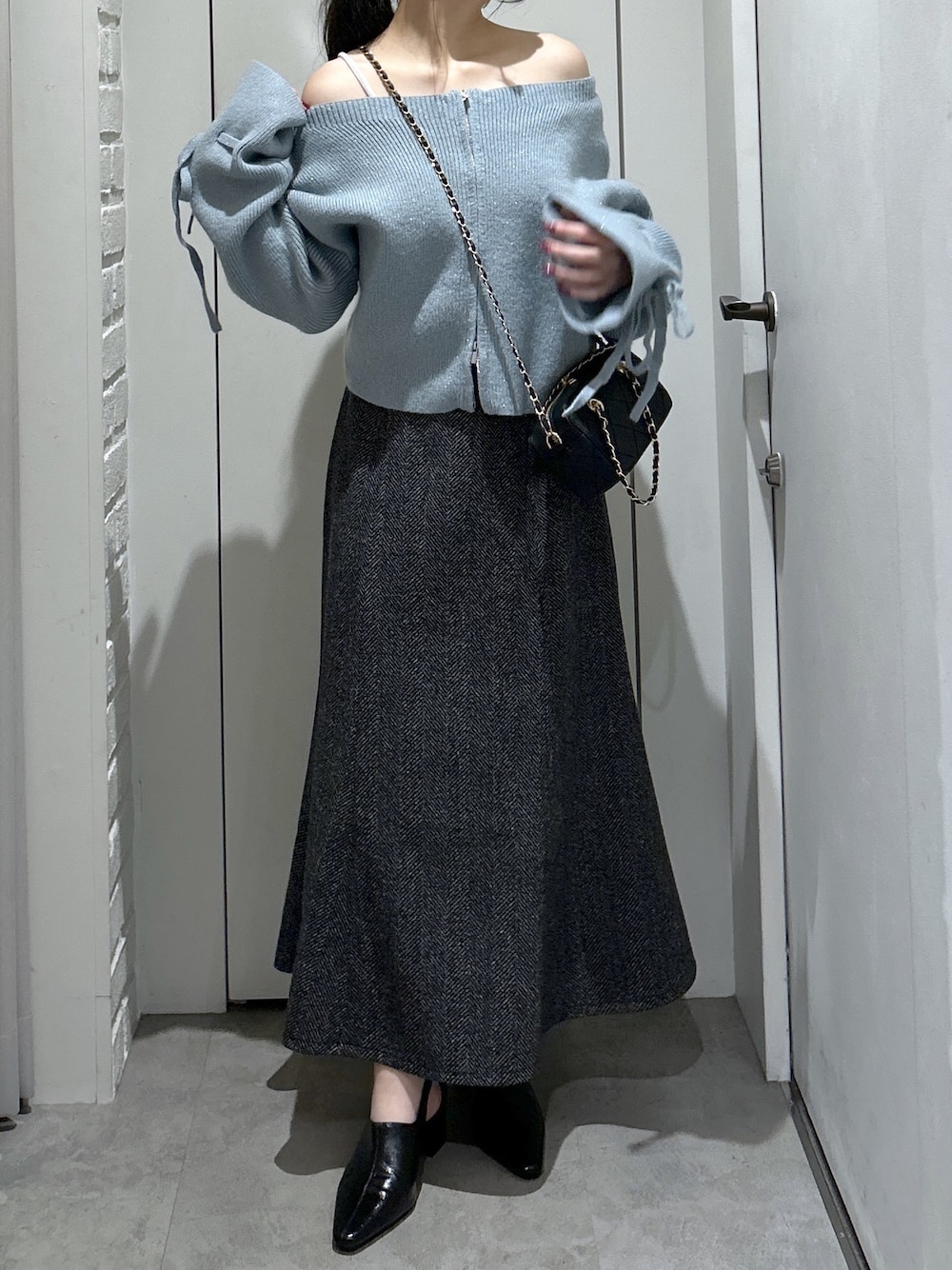 ブルー系のニット/セーター、ブラック系のスカート、ブラック系のパンプスを着用したレディースの冬コーディネートの1枚目の写真